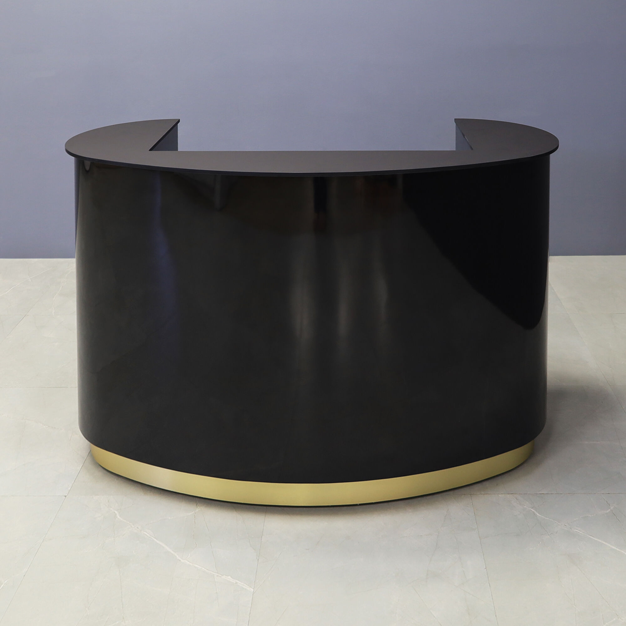 60-inch The Pill Custom Reception Desk with 1/2" black traceless engineered surface top, black gloss laminate main desk, and brushed gold toe-kick, shown here.