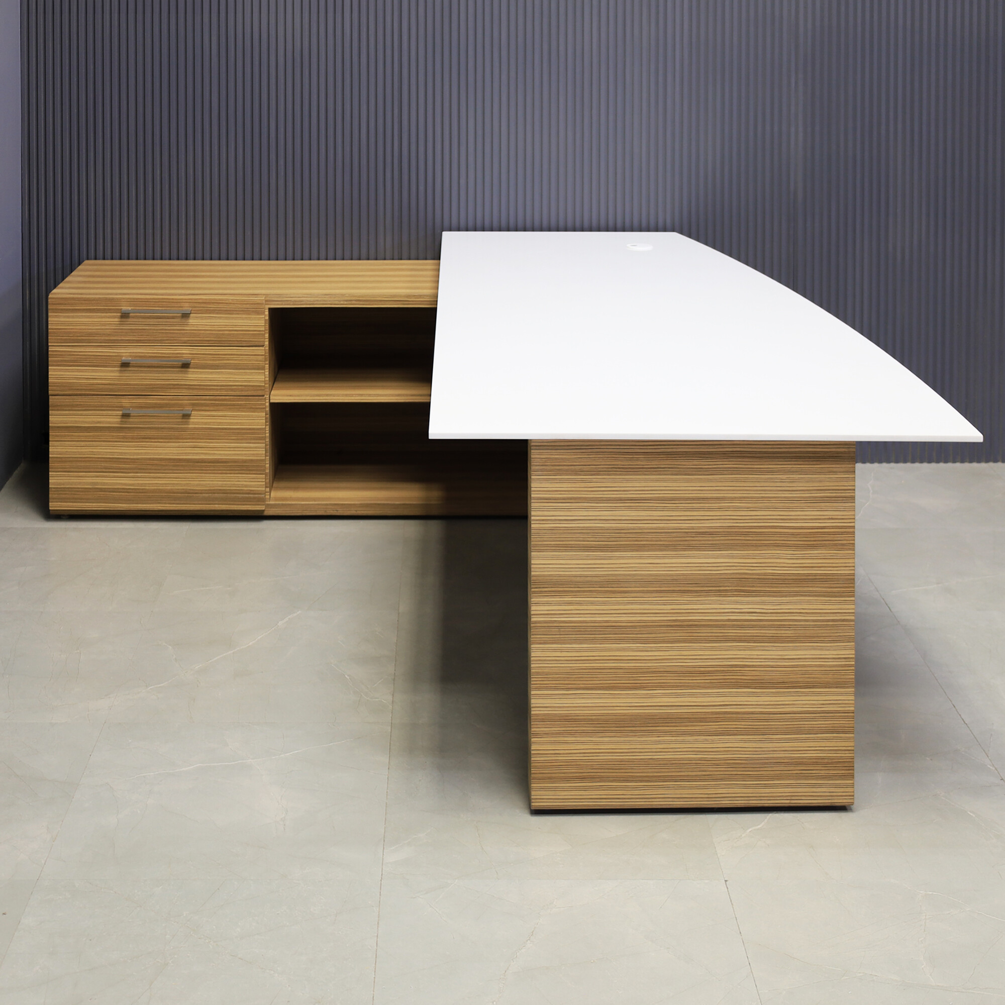 84-inch Avenue Curved Executive Desk with credenza on the left side when sitting, with 1/2" white solid engineered surface top, wood veneer base and credenza, and storm gray matte laminate privacy panel, shown here.
