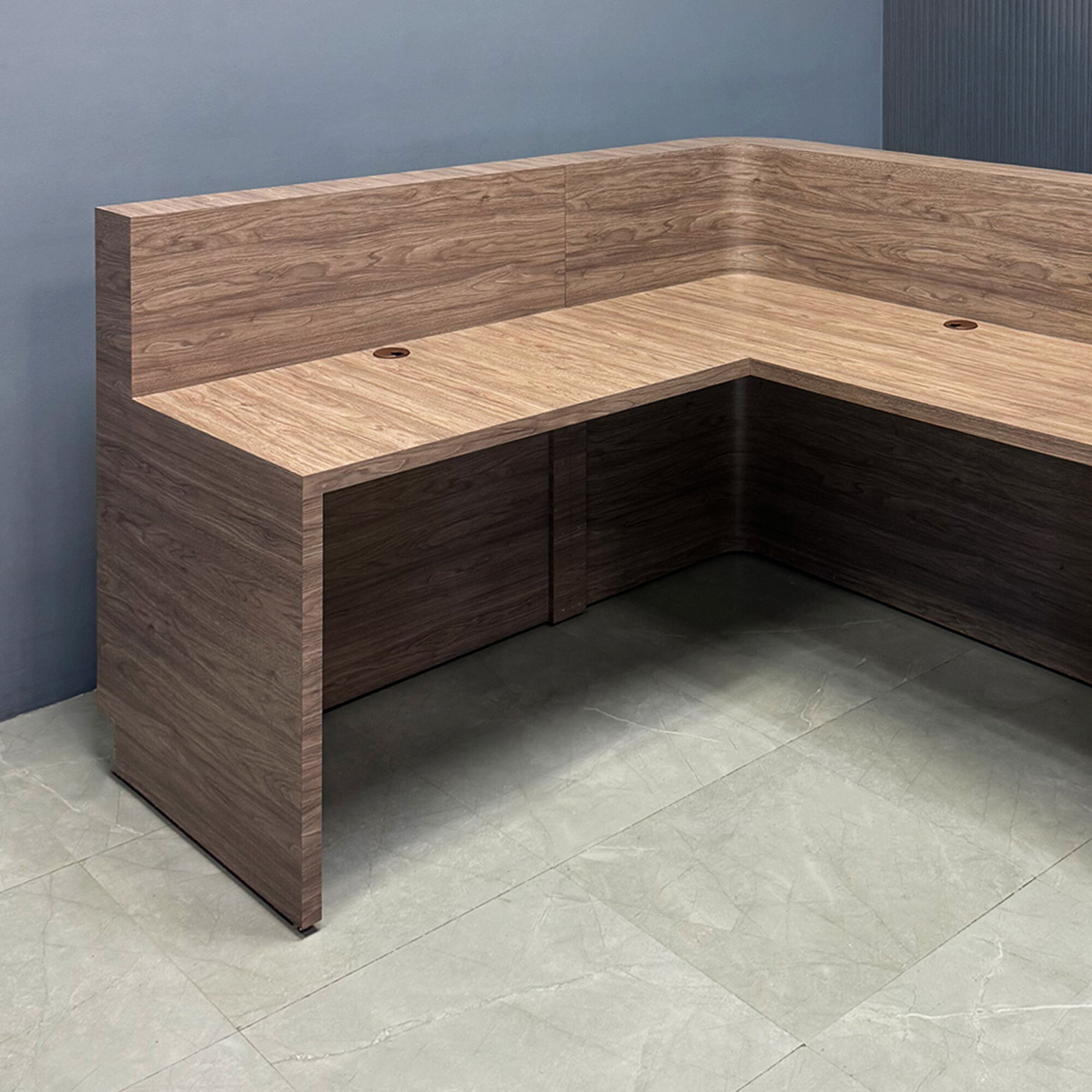 72-inch Nola L-Shape Custom Reception Desk with the l-panel on the right side when facing front with a 36-inch high extension. The main desk is covered in hazel walnut matte laminate and the toe-kick in brushed aluminum.